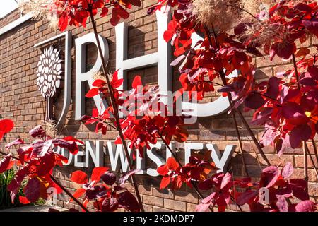 Cartello e logo RHS Garden. Wisley ingresso visto attraverso fogliame rosso autunnale in condizioni di sole Wisley Gardens Surrey UK Foto Stock