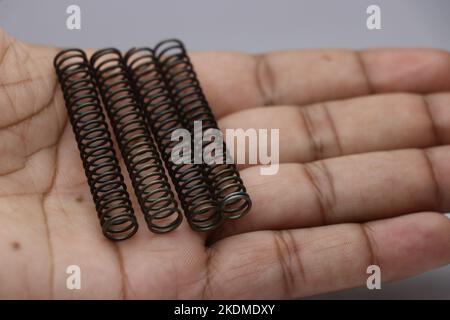 Quattro molle elicoidali di compressione in acciaio tenute in mano. Molle metalliche come sostituzione di parti meccaniche Foto Stock