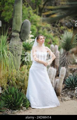 Sposa in piedi in un giardino di Cactus Foto Stock