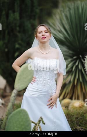 Sposa circondata da piante di Cactus in un giardino nel tardo pomeriggio Foto Stock