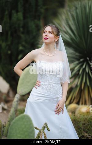 Sposa circondata da piante di Cactus in un giardino nel tardo pomeriggio Foto Stock