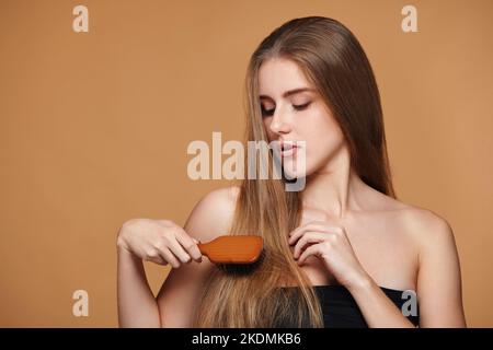 la donna pettina i suoi lunghi capelli naturali con una spazzola di legno Foto Stock