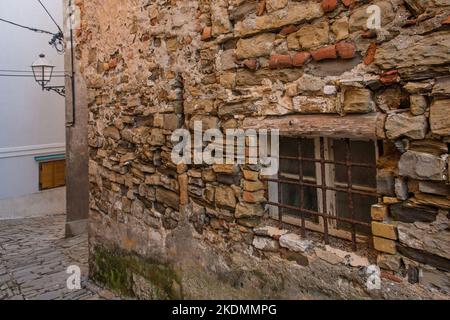 Una finestra barrata in un vecchio edificio residenziale in pietra nel centro storico di Piran, sulla costa della Slovenia Foto Stock