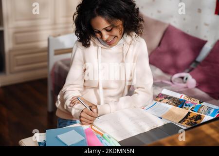 Ragazza teen africana che fa i compiti con il laptop nella sua stanza Foto Stock