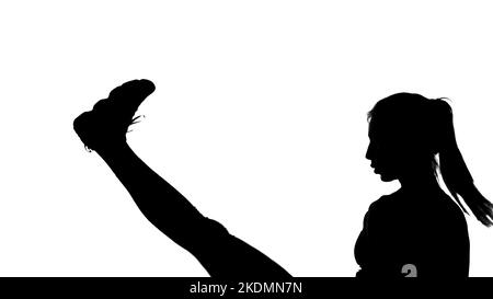 su uno sfondo bianco, un'ombra, un contorno nero di una figura femminile che fa i movimenti di boxe, una lotta con un'ombra, calci, kickboxing, imitazioni di colpi, tecniche di combattimento,. Foto di alta qualità Foto Stock