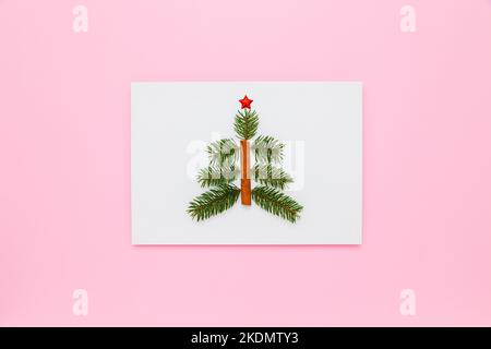 Composizione per Natale, Capodanno con spazio per il testo. Bianco carta con albero di Natale nel mezzo su pastello rosa piatto backgrou Foto Stock