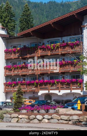 I balconi di un hotel in stile bavarese a Leavenworth, Washington, USA traboccano di scatole di fiori di petunie viola e viti di piselli. Foto Stock