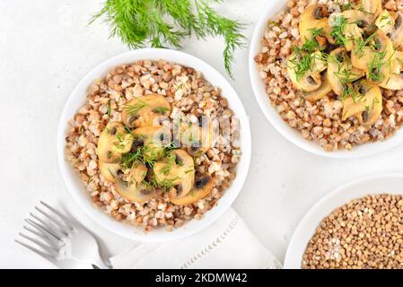 Porridge di grano saraceno con funghi arrostiti in ciotola bianca. Vista dall'alto, piatto Foto Stock