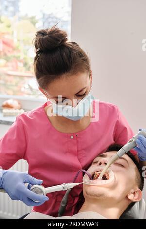 Vista dall'alto del processo di pulizia dei denti del paziente. Spazzolare i denti con getto d'acqua e detergente per saliva. Guance del riavvolgitore sulle labbra. Il concetto o Foto Stock