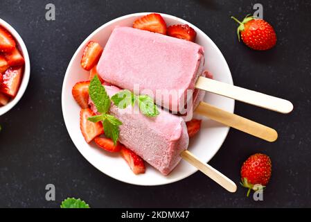 Popsicle di gelato alla fragola su piatto bianco. Vista dall'alto, disposizione piatta Foto Stock