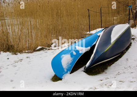 Due canoe blu sdraiate nella neve sulla spiaggia in inverno. Foto Stock