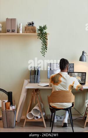 Vista posteriore verticale di un uomo nero creativo che costruisce modelli 3D digitali sul luogo di lavoro dell'ufficio domestico Foto Stock