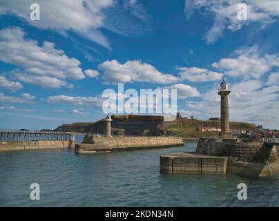 Ingresso al Whitby Harbour con il Whitby West Pier Lighthouse in primo piano, North Yorkshire, Inghilterra Foto Stock