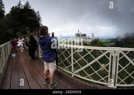 Fussen, Germania - 19 agosto 2022: Castello di Neuschwanstein a Fussen, famoso punto di riferimento della Baviera, Germania. Vista su una giornata nuvolosa con persone e touri Foto Stock