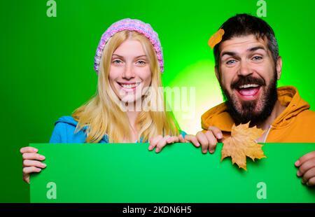 Coppia sorridente con lavagna pubblicitaria vuota. Tendenze moda per l'autunno. Vendita stagionale, vacanze autunnali. Foto Stock