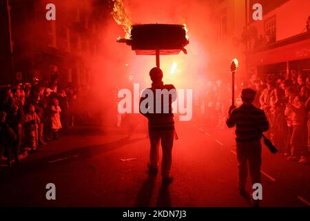 Jason Winter, capitano di barili di Tar per Borough, porta un barile fiammeggiante lungo la strada principale di Lewes. Foto Stock