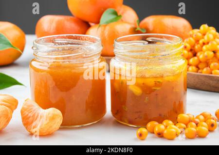 Vasetti di sano biancospino e marmellata di mandarini. Piatto di bacche di biancospino e frutti di mandarino arance sullo sfondo. Foto Stock