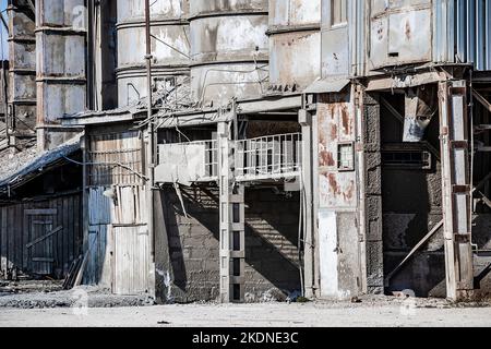 Vecchio sito di costruzione distrutto. Impalcature arrugginite e attrezzature da costruzione. Edifici industriali in fabbrica abbandonata. Foto Stock