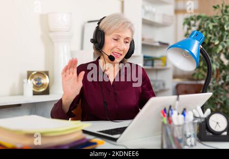 Donna in auricolari che lavorano in ufficio Foto Stock