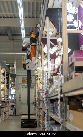 CZECHIA, scaffali con merci in un supermercato con dipendenti che lavorano su una piattaforma di sollevamento Foto Stock
