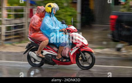 SAMUT PRAKAN, THAILANDIA, 21 2022 SETTEMBRE, coppia in impermeabile guidare sotto la pioggia Foto Stock