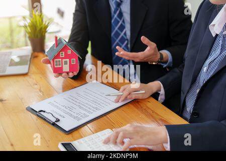 Garanzie, ipoteche, firma, interessi su prestiti, agenti immobiliari stanno stipulando accordi con i clienti per acquistare case e terreni e firmare un contratto Foto Stock