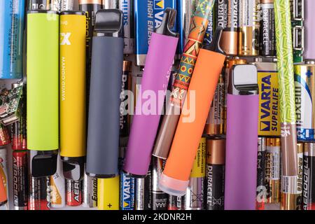 Praga, cz - 08 novembre 2022: Mucchio di varie sigarette elettroniche usa e getta su pile di vecchie e usate batterie, diversi tipi e dimensioni, rifiuti re Foto Stock