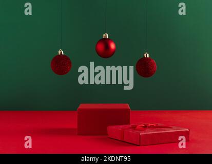 Concetto creativo di Natale fatto di podio e baubles rosso su sfondo verde audace. Concetto minimo di annuncio di Capodanno. Mostra mock-up per il pro Foto Stock