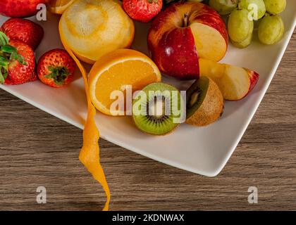 Ancora vita di colorati frutti tropicali su un piatto quadrato su una superficie di legno. Foto Stock