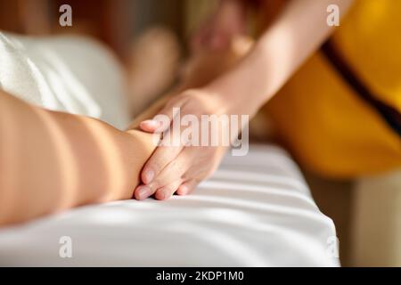 Massaggiatrice che fa lunghi tratti scivolanti quando massaggia il corpo di una cliente femminile Foto Stock