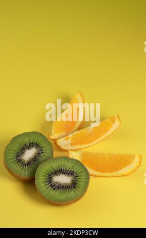 primo piano di kiwi e fette di arancia su sfondo giallo Foto Stock