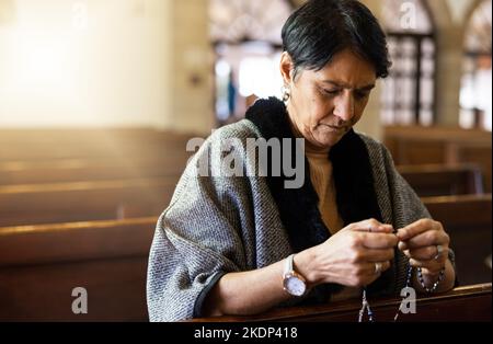 Pregate, donna anziana e pregate in chiesa con un rosario per la religione, il culto e la lode di Dio, pacifica e calma. Santa, pace e preghiera del Messico Foto Stock