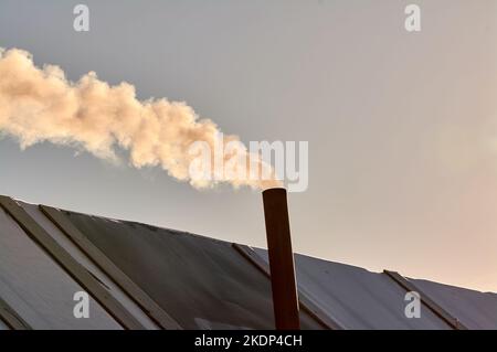 il fumo proviene dal camino della borghesia. la stufa è riscaldata. Foto Stock