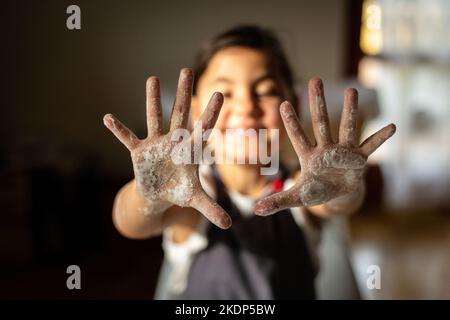 primo piano delle mani del bambino sporche di farina Foto Stock