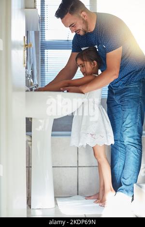 Lascia lavare via quei germi. Un padre che aiuta sua figlia lavarsi le mani al lavandino del bagno. Foto Stock