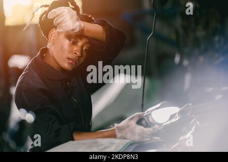 donna africana lavoratore duro lavoro sudore stanco per ragazza meccanica controllo motore garage Foto Stock