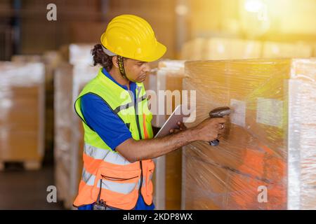 lavoratore indiano nel settore della logistica che lavora sistema di gestione dell'inventario utilizzando lettore di codici a barre e tablet computer Foto Stock