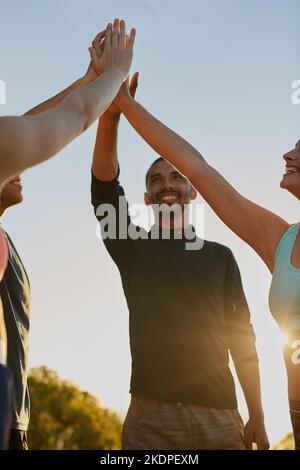 Lavorate sodo e siate fieri di voi stessi. Un gruppo di fitness che si dà a vicenda un alto cinque come squadra. Foto Stock