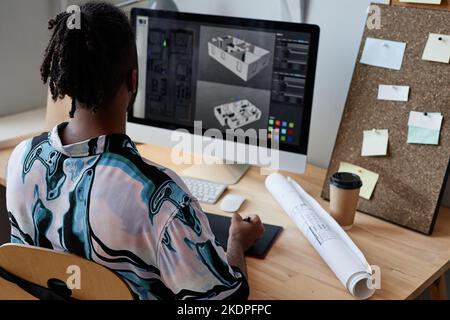 Vista posteriore del designer digitale maschile che crea il modello 3D di casa sul posto di lavoro, spazio copia Foto Stock