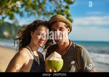 L'estate è proprio come piace a noi. Ritratto di una giovane coppia felice che si gode un cocktail mentre si rilassa sulla spiaggia. Foto Stock