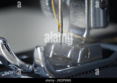 Ago con filo giallo e piede per macchina da cucire. Fotografia macro. Foto Stock