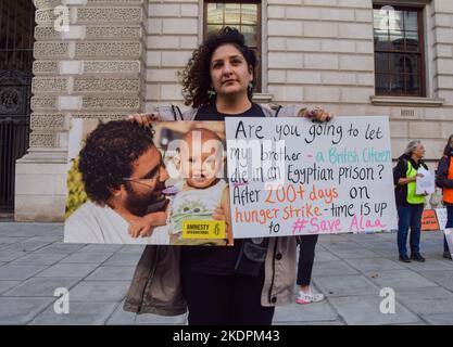 Londra, Regno Unito. 26th ottobre 2022. Sanaa Seif ha una foto di suo fratello al di fuori dell'Ufficio degli Esteri, del Commonwealth e dello sviluppo. Sanaa Seif, la sorella di Alaa Abdel Fattah, un attivista britannico-egiziano incarcerato in Egitto, che è stato in sciopero della fame per oltre 200 giorni, ha organizzato un sit-in al di fuori dell'ufficio degli esteri di Westminster. Ha dormito in una tenda all'aperto e continuerà a farlo fino all'inizio del COP 27 o fino a quando il Ministro degli esteri James non accetterà abilmente di incontrarla e intensificherà gli sforzi per il suo rilascio. Foto Stock