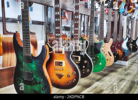 Una fila di chitarre elettriche a corpo solido appese su un banco espositore in un negozio di musica Foto Stock
