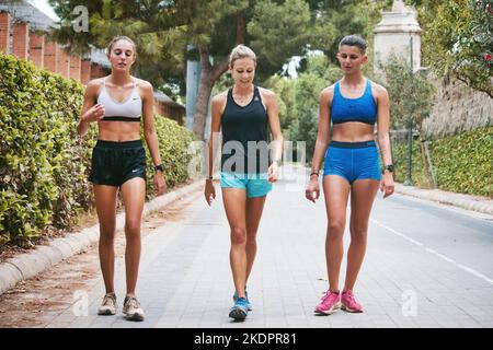 Valencia, Spagna - Settembre 12 2022: Tre giovani donne sportive che indossano shorts da running e top walking attraverso il parco Turia di Valencia Foto Stock