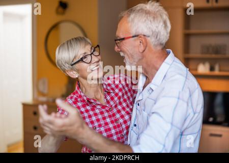 Felice coppia anziana sta ballando a casa. Anziani che hanno tempo piacevole insieme. Foto Stock
