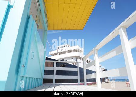 Port-Barcarès, Francia - 2022 ottobre; ex nave da crociera le Lydia sulla spiaggia vista da una torre di bagnino dai colori vivaci sullo sfondo del cielo blu Foto Stock