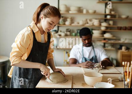 Vista laterale ritratto di giovane donna che forma a mano ciotola in ceramica in accogliente studio di ceramica, spazio copia Foto Stock