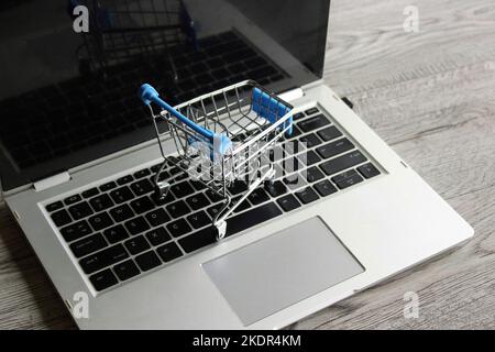 Portatile e mini carrello su tavolo di legno. Concetto di shopping online Foto Stock