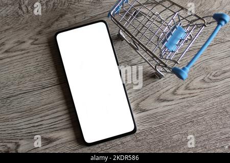 Smartphone con schermo bianco vuoto all'interno del carrello della spesa con spazio per le copie. Concetto di shopping mobile Foto Stock
