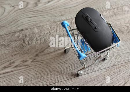 Mouse per computer all'interno del carrello della spesa su un tavolo di legno con spazio copia. Concetto di shopping online Foto Stock